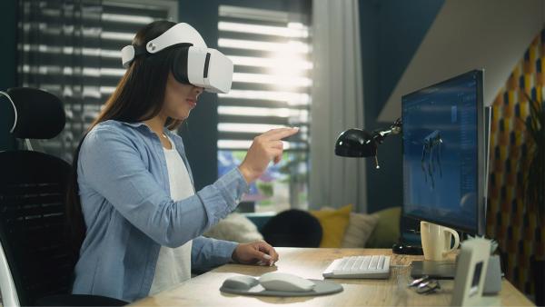Woman sitting at desk and using VR headset to work
