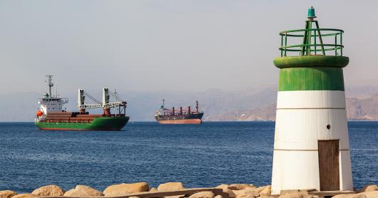 Small lighthouse on the coast of Aqaba, Jordan, with cargo ships in the background. 