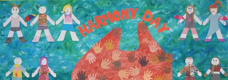 A child's artwork with paper dolls holding hands across Australia and hand prints of various colours with the words 'Harmony Day' across the top.