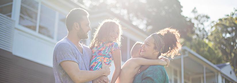 Stock image of a First Nations family outside a suburban home