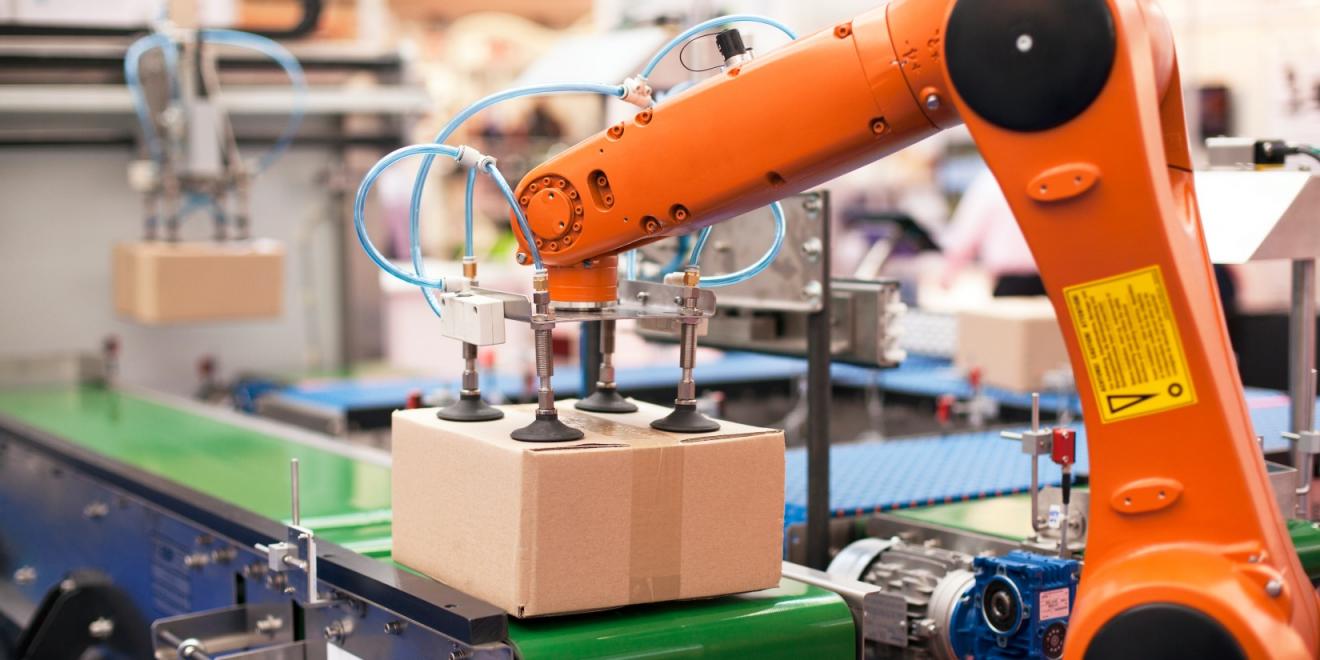 An articulated robotic arm grabs a package off a conveyor belt