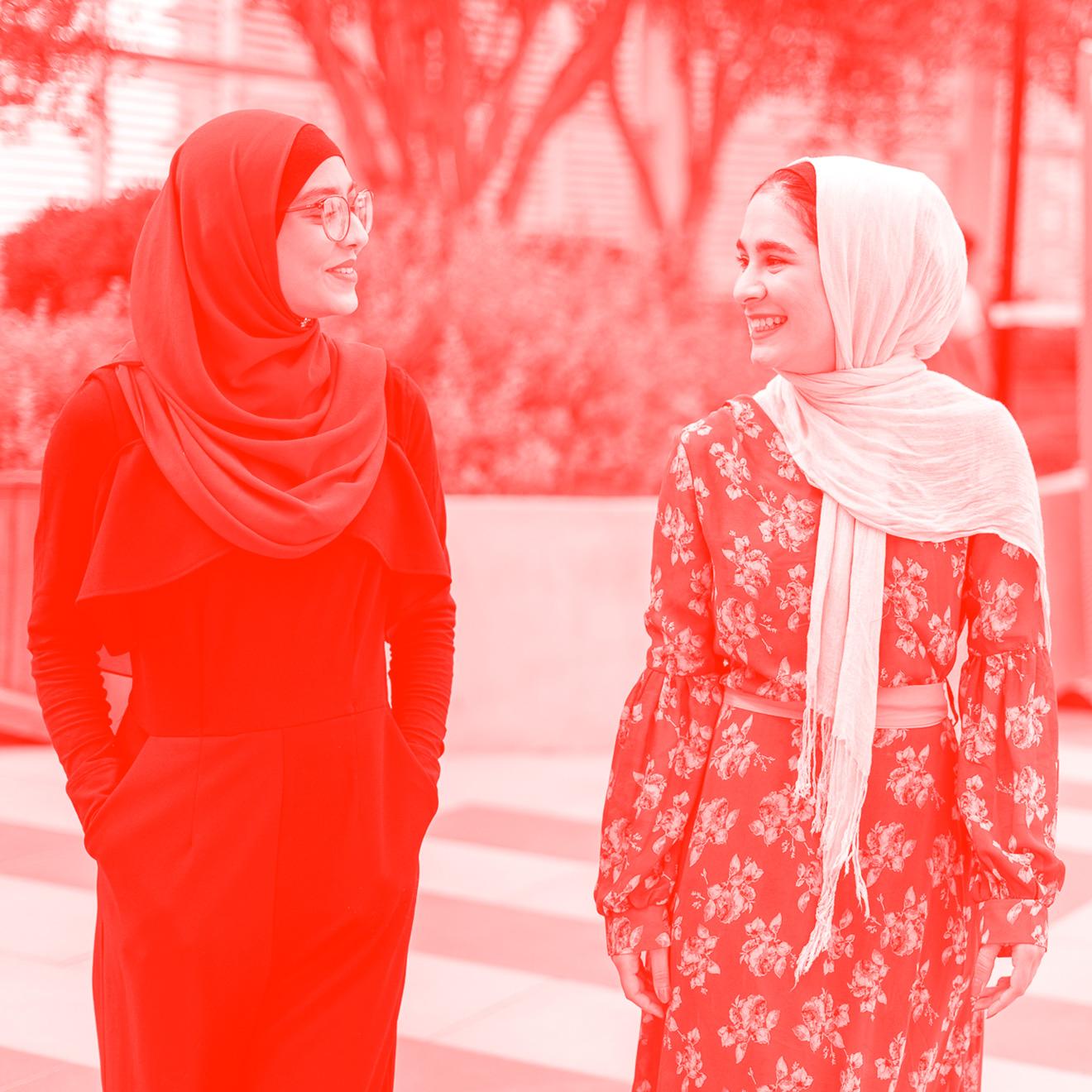 Two young women in hijabs smiling and walking.