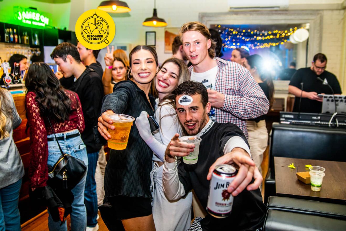 group of friends smiling at pointing at the camera, drinks in hand