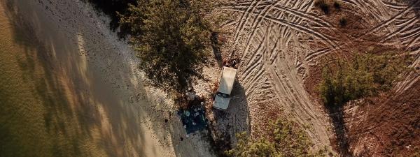 Still from Rarranhdharr - Late dry season - The Mulka Project 2020 - a beach camp and vehicle filmed from above, multiple tyre tracks form a pattern in the sand
