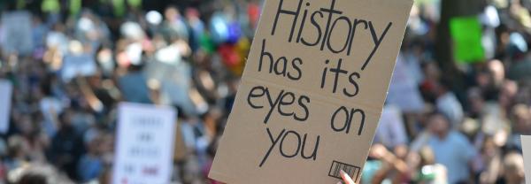 Sign saying ‘History has its eyes on you’ held up in a protest rally