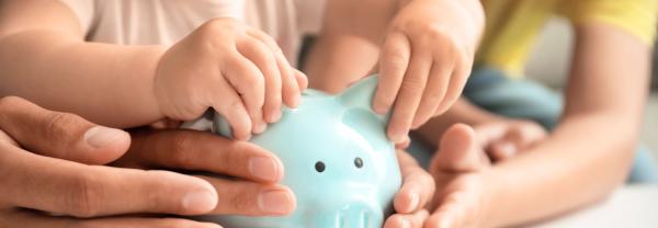Child and parents hands holding a piggy bank