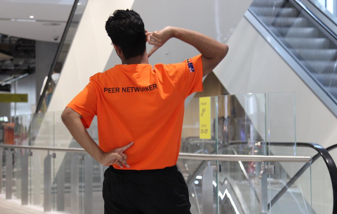 A Peer Networker pointing at his shirt that reads 'Peer Networker'