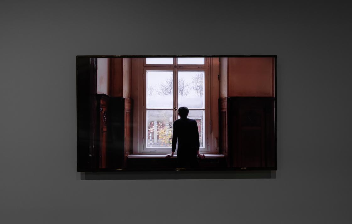 A tv monitor showing an image of a person looking out of a window