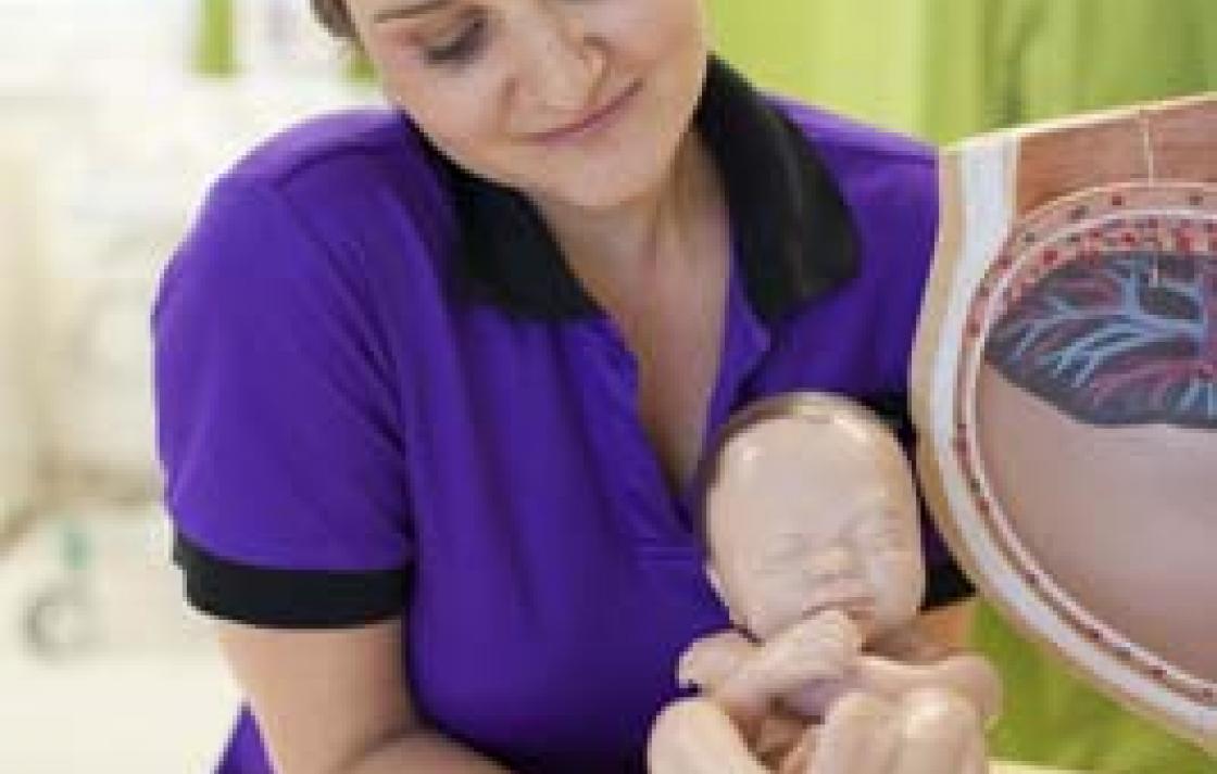 Midwife student examining model of baby 