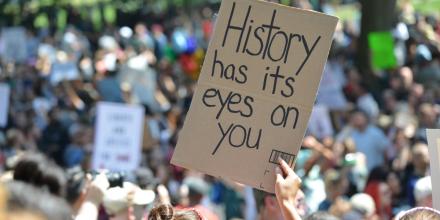 Sign saying ‘History has its eyes on you’ held up in a protest rally