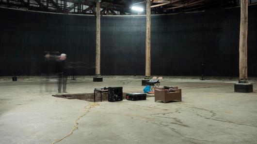A person standing in a warehouse, with an installation set up in the middle