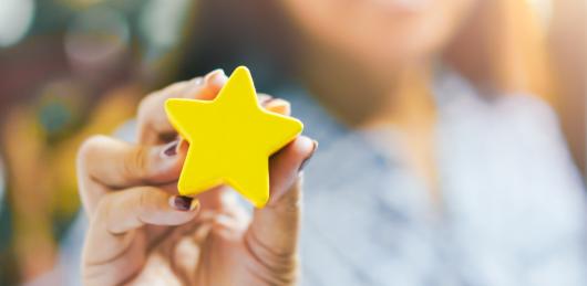 Close up image of a person's hand holding a 3D yellow star