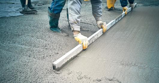 a construction worker levels wet concrete with a tool.