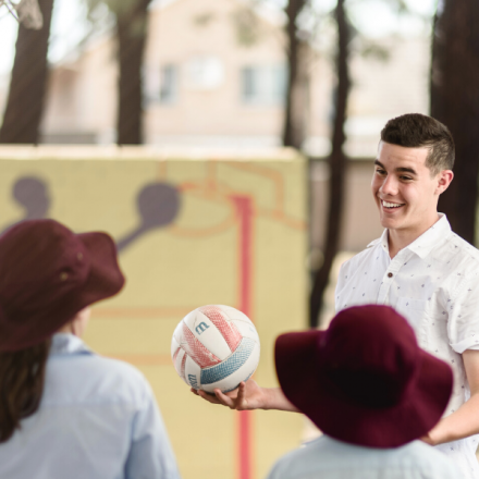 A male student teacher playing sport with primary students
