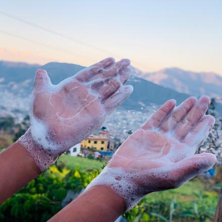 Hands with soap suds with village in background
