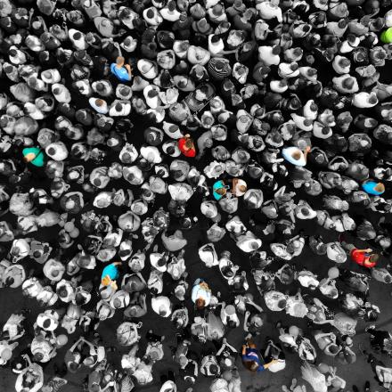 Special people amid the crowd concept with colorful persons amid the monochrome people. Top view from drone. 