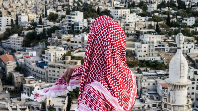 A woman wearing Arab headdress overlooking a city