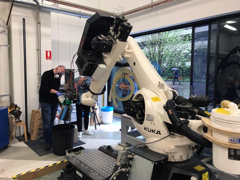 Staff use a large robot arm to 3D print EPS