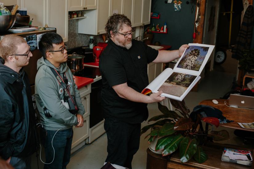 Photographic artist John Chiara shows two UTS students photographs from a book.