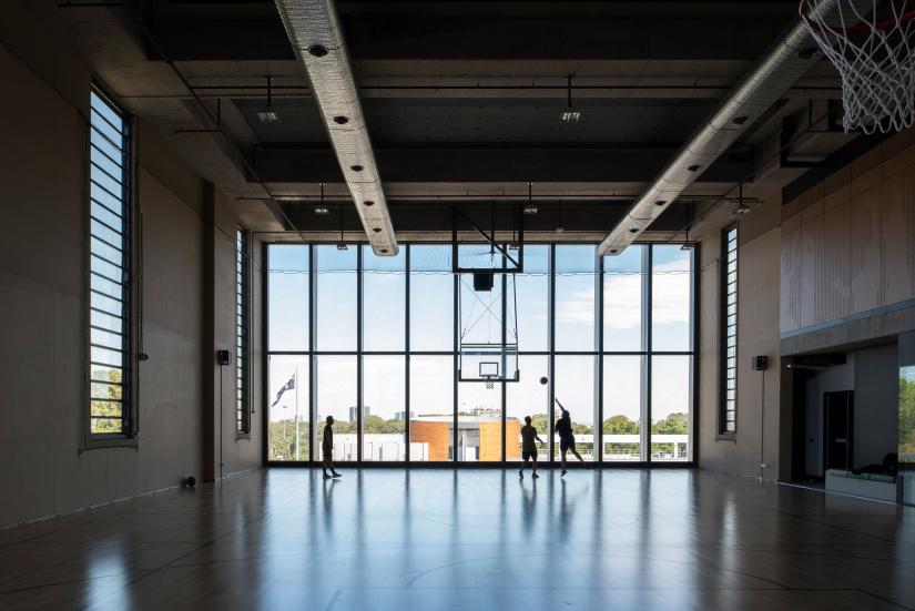 A hall with 3 people playing basketball