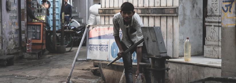 Young man pumps water from a well in a village street