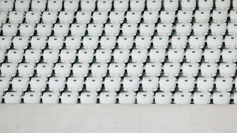 Hundreds of empty white seats in a sporting stadium