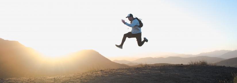 person jumping on a mountain