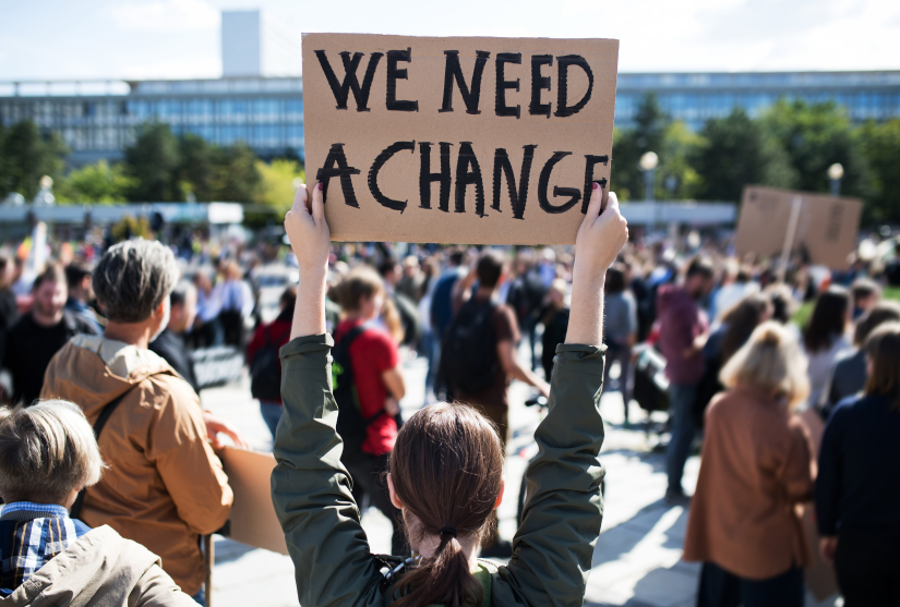A protester holds a sign reading 'We need a change'