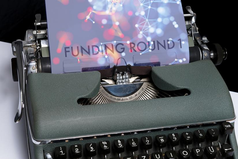 typewriter with Funding Round 1 typed on paper with bright colours and connections