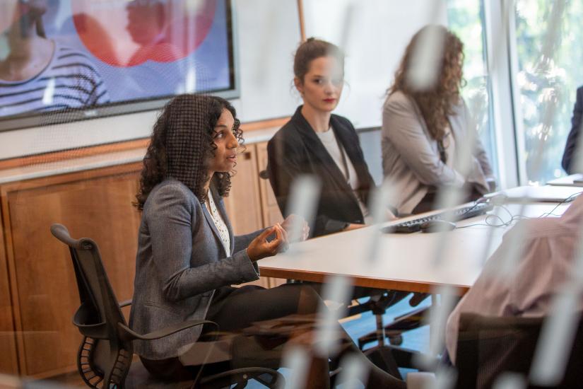 A view of a boardroom meeting, in which 3 women are visible