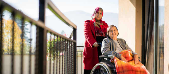 Muslim woman standing behind elderly women in wheelchair