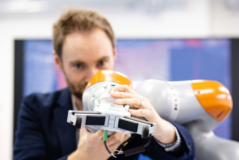Close up image of man adjusting collaborative robotics equipment
