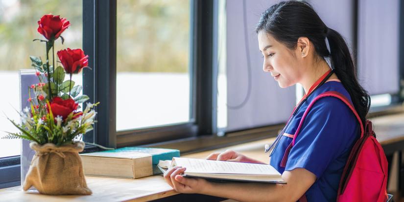 Nurse in scrubs studying at a desk
