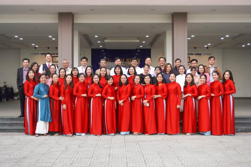 Staff of Phu Xuan University stand in traditional dress and smile for the camera