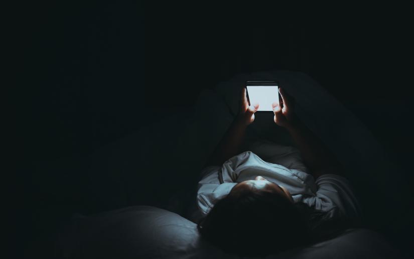 Person lying down using his phone in a dark room