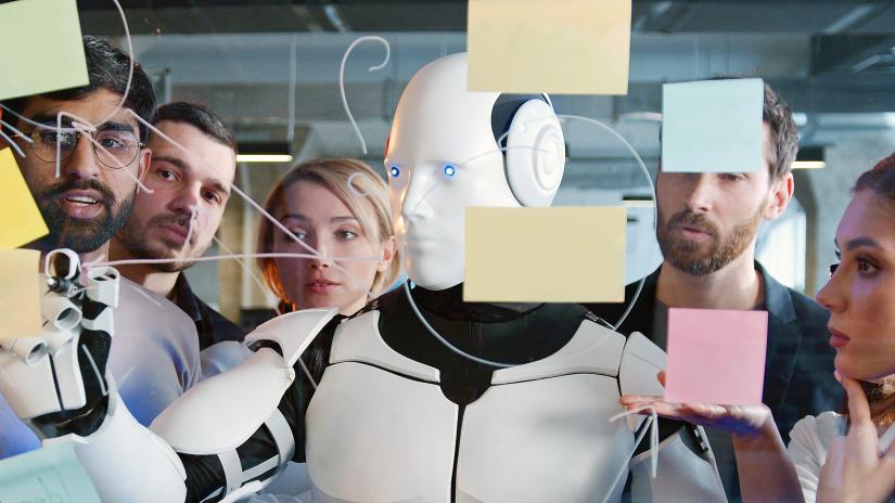 Stock image of a robot brainstorming on a clear board with a group of people