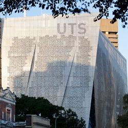 A large, rectangular building covered in aluminum screens with a perforated binary code