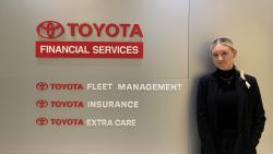 Tara Holmes stands beside Toyota Financial Services sign