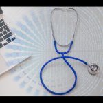 stethoscope next to a laptop with Abstract date image in background