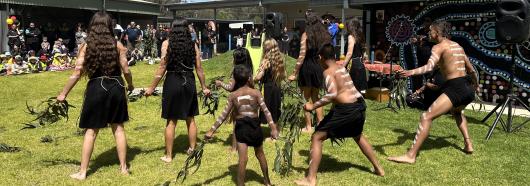 A group of Indigenous dancers perform for a crowd
