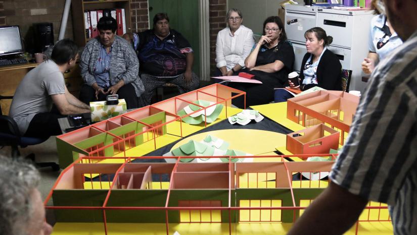 A scale model of the design, with surrounding people observing and discussing.
