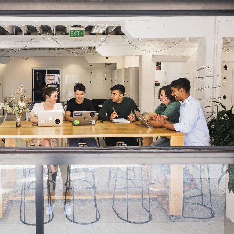 Students sitting at a communal area in the UTS Startups office with laptops