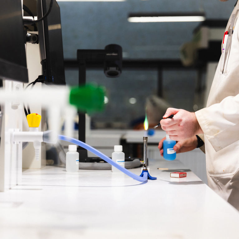Person in Science lab working with a Bunsen burner.