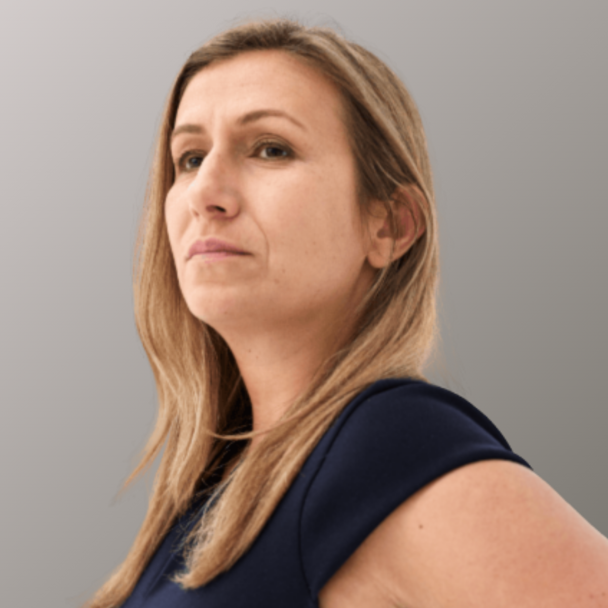 Portrait of Flavia Tata Nardini against a grey gradient background. She has blonde hair and a black top.