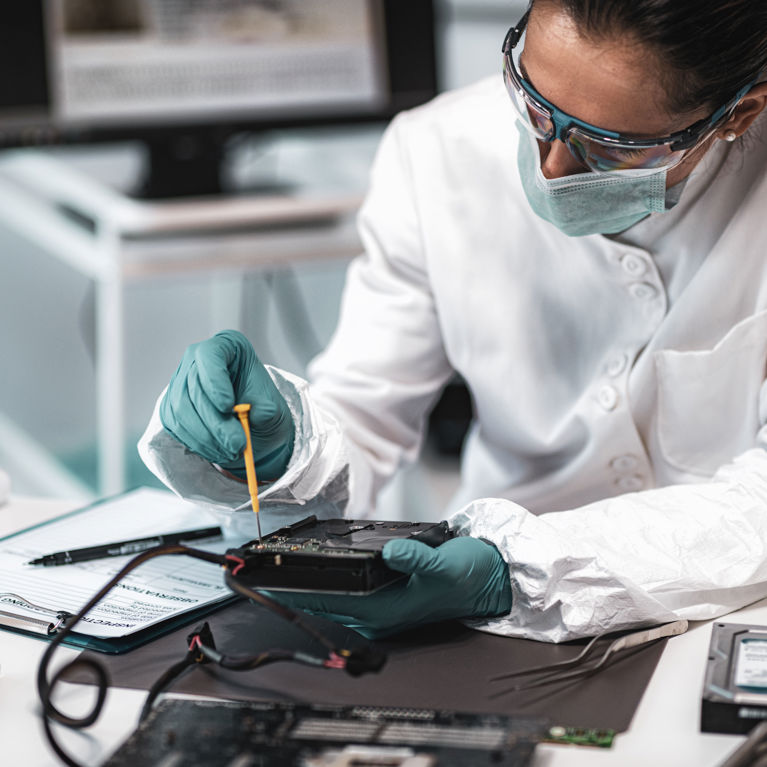 Person in white coat and mask using tools.