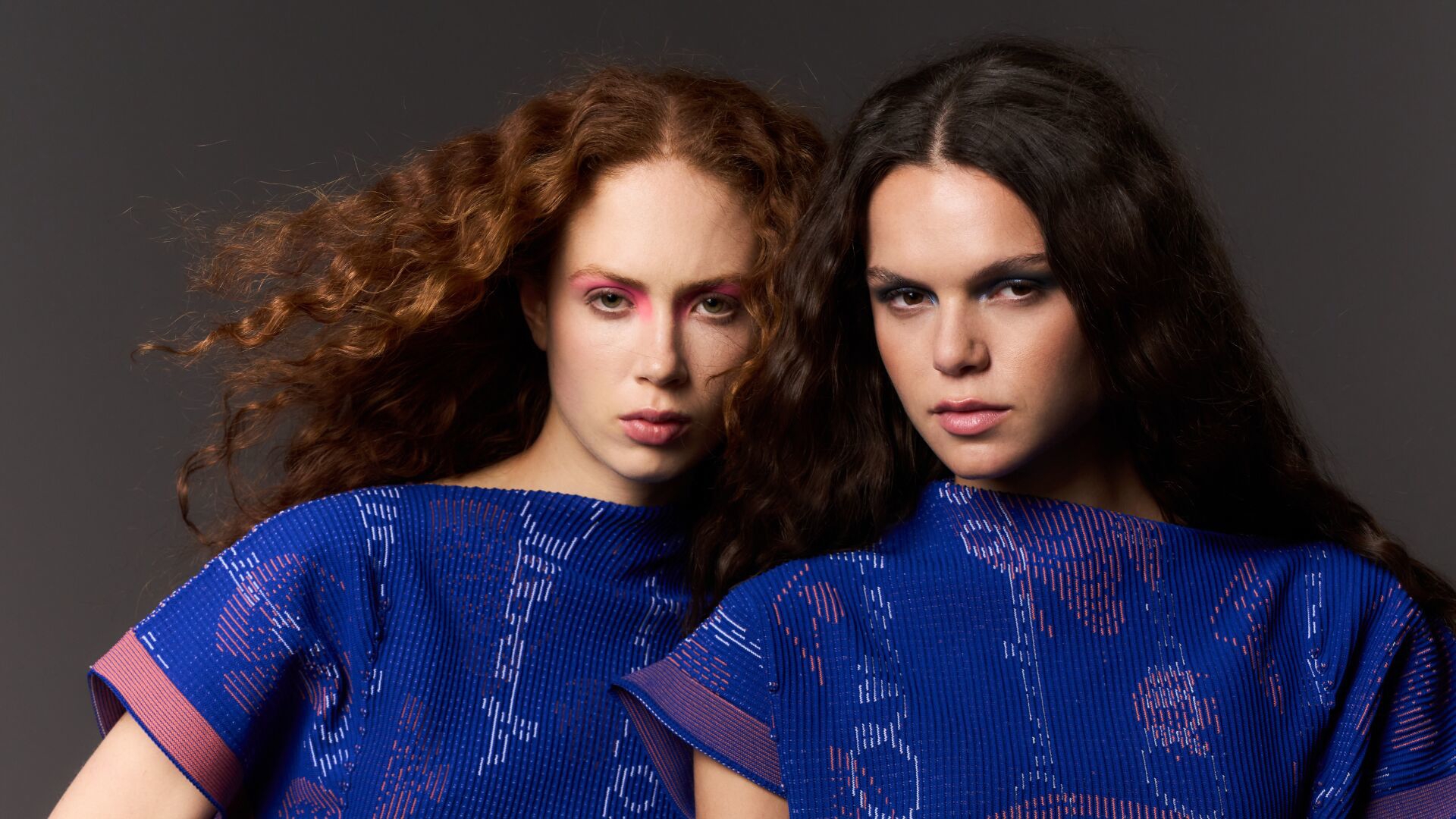 Two models wearing dark blue knitted dresses featuring aquatic animals and plants