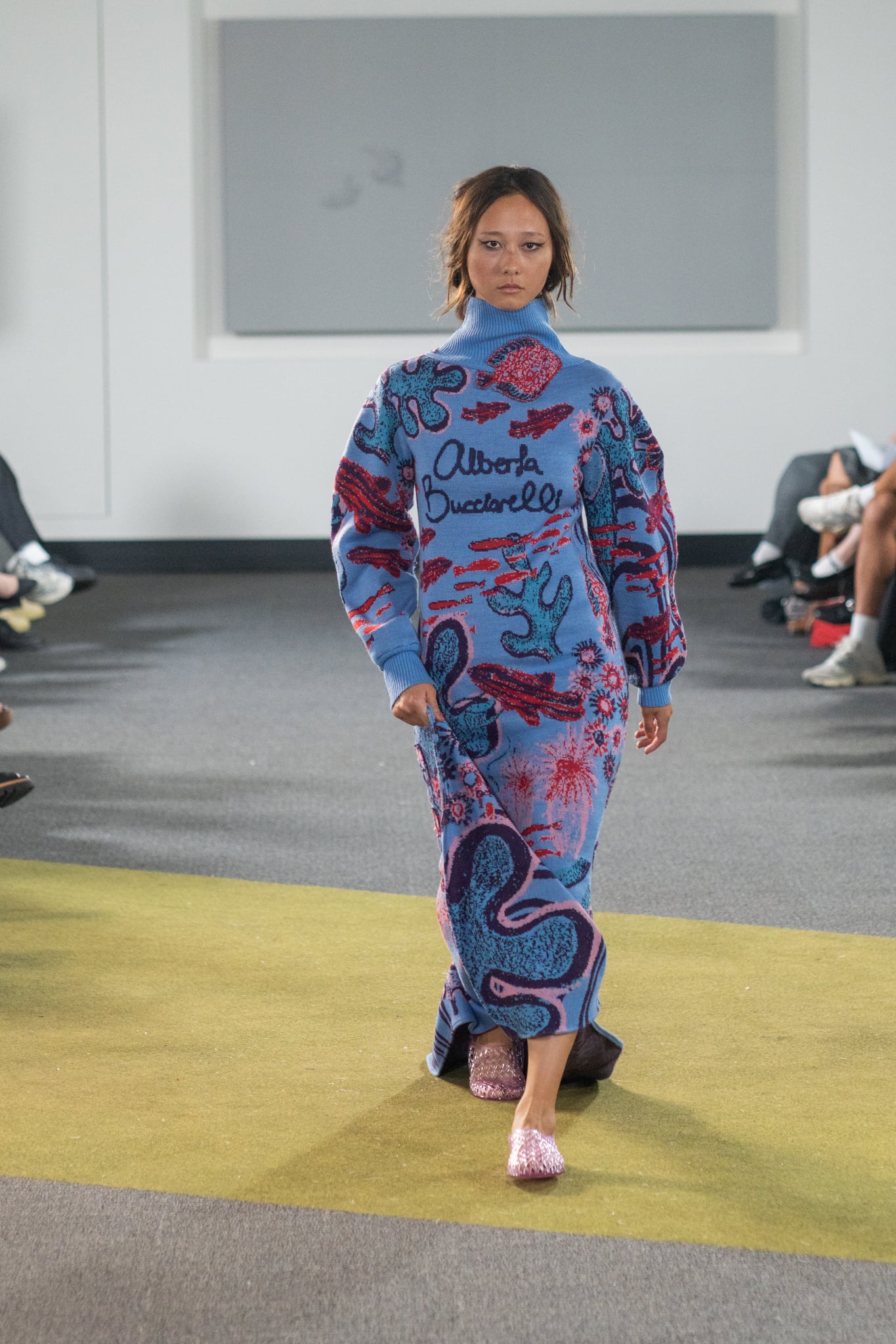 Fashion model on the runway wearing a light blue knitted dress featuring aquatic animals and plants