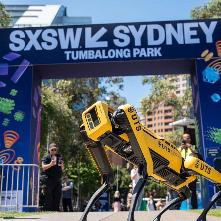 Spot the robot dog stands in front of the SXSW Sydney 2024 sign outside Tumbalong Park.