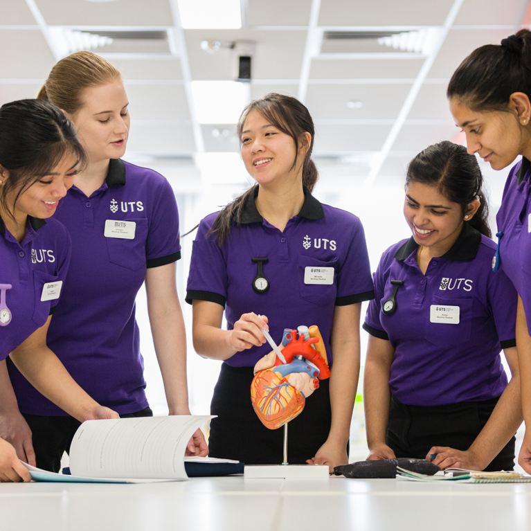 Five nursing and midwifery students looking at a model of a heart
