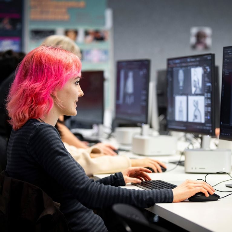 Student sitting in front of computer with animation software on the screen.
